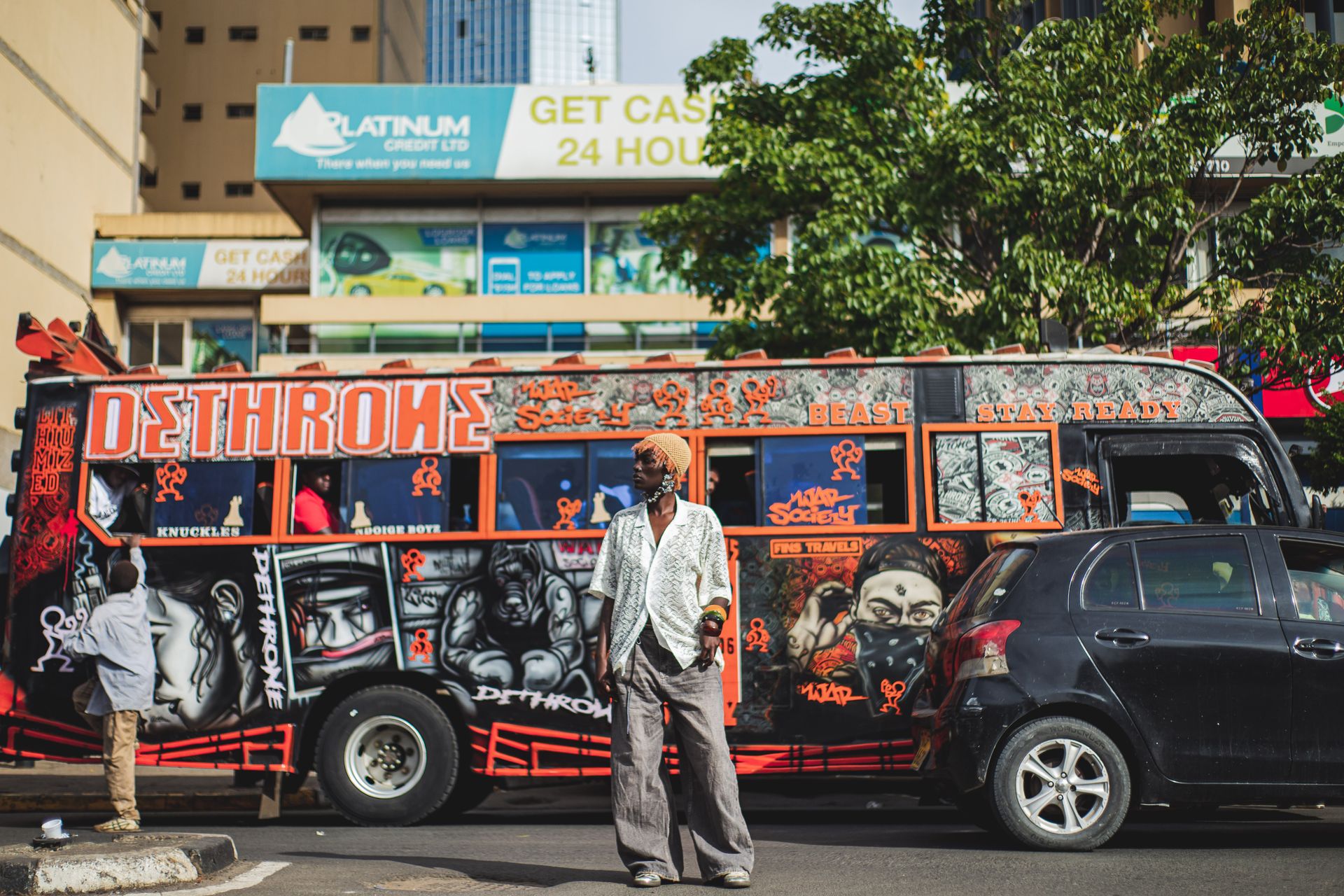 A woman stands in front of a boldly decorated red and black van with street art in Nairobi, Kenya